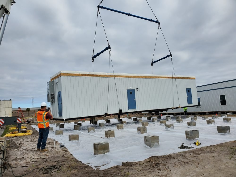Modular building module being craned onto its foundation blocks