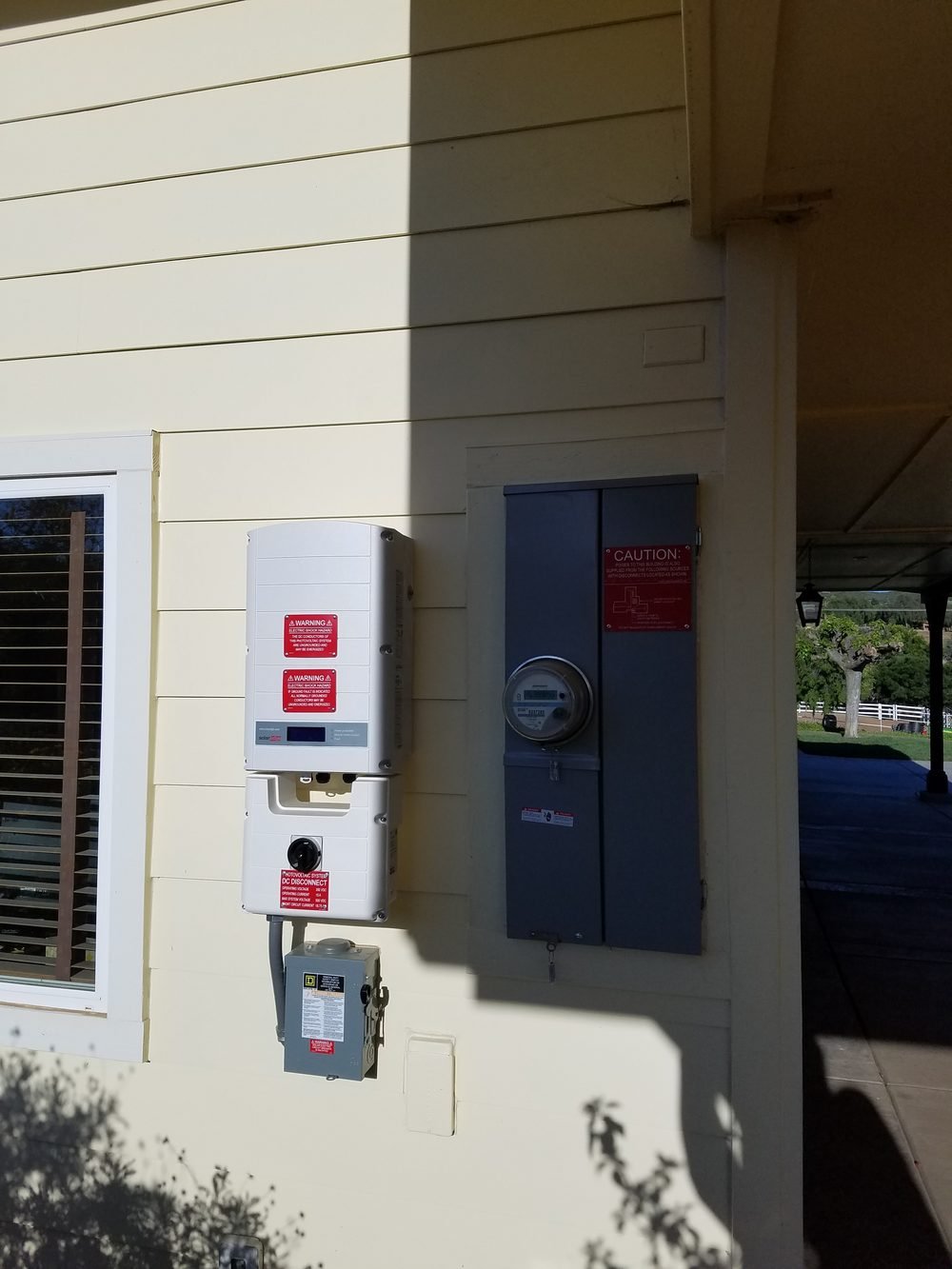 Solar inverter, DC disconnect and utility meter panel on a house exterior
